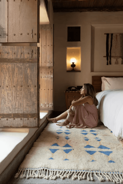 A woman enjoying The Symbols by Fatima Rug – A Masterpiece of Craftsmanship in a cozy bedroom setting.