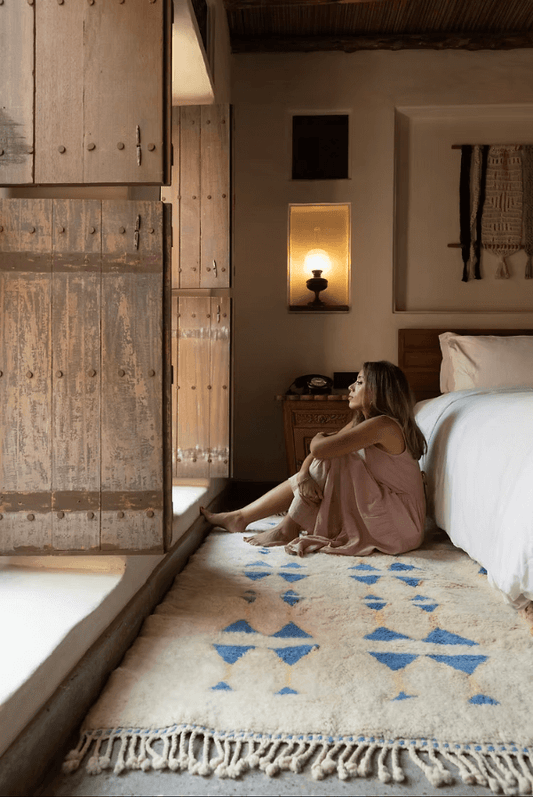 A woman enjoying The Symbols by Fatima Rug – A Masterpiece of Craftsmanship in a cozy bedroom setting.