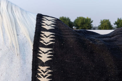 Char Noir – Black & Ivory Moroccan Rug draped over a white horse showing intricate geometric patterns.