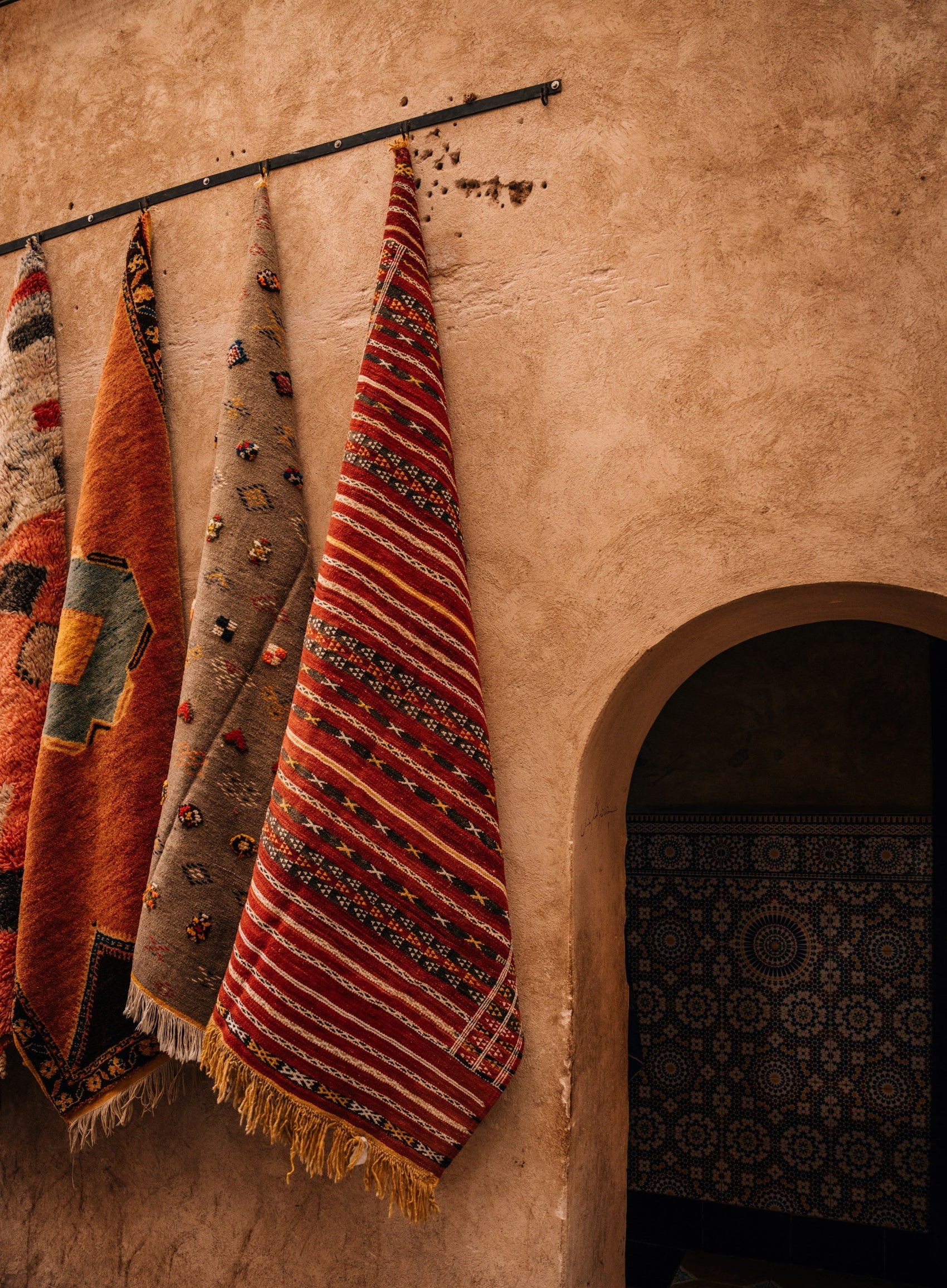 Decorative rugs with intricate patterns hanging on a wall.